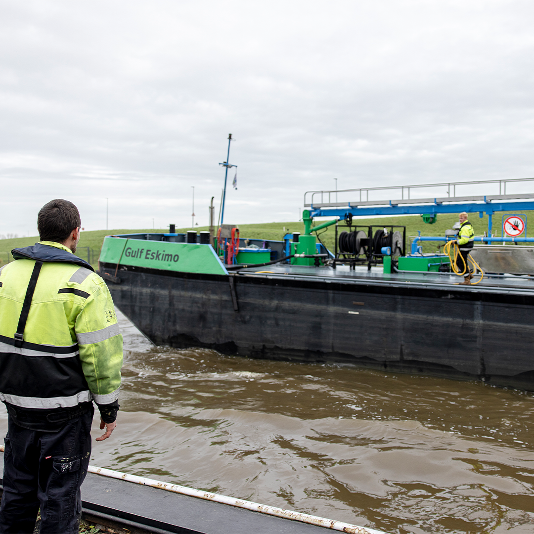 Man in safety gear observes the bunker vessel ‘Gulf Eskimo’ docking at the quay, while a crew member on deck handles hoses and equipment.